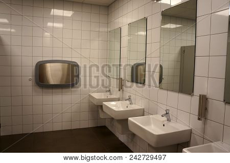 Row Of Modern White Ceramic Wash Basin And Mirror In Toilet