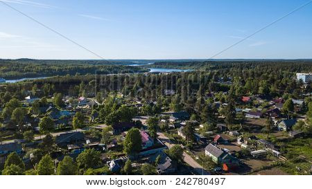 Russian village with wooden houses. Svir river and summer green forests of Leningrad region, Russia. Flying over roofs. 