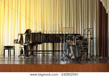 A Drum Set On A Black Piano Background In A Concert Hall.