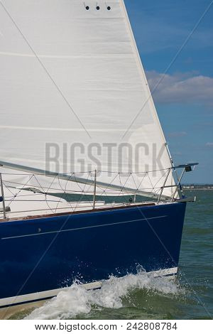 Close up of sailing boat, sail boat or yacht with a blue hull and white sails at sea