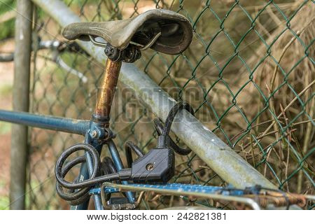 Old Bicycle Secured With A Bicycle Lock - Detail Of Bicycle Lock And Saddle