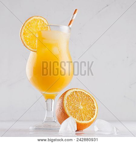 Yellow Cold Juice With Ice Cubes, Straw And Half Oranges On Soft White Plater Background, Square, Cl