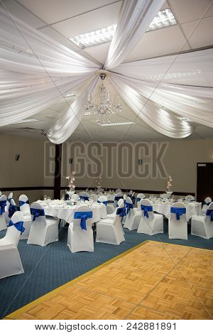 A Wedding Reception Set Up With A Blue And White Colour Theme, Showing The Wooden Dance Floor And Th