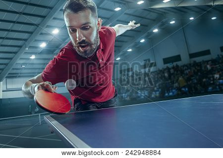 The Table Tennis Player In Motion. Fit Young Sports Man Tennis-player In Play On Sport Arena Backgro