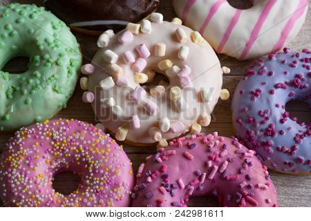 Assortment Of Colorful Frosted Doughnuts. Glazed Sprinkles With Marshmallow And Chocolate On Wooden 