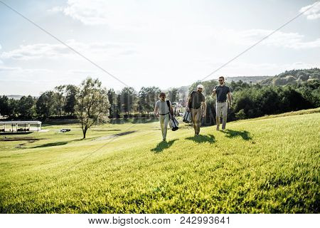Three Smiling Men In Sunglasses Holding Golf Clubs Outdoors