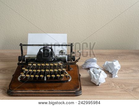 Old Fashioned Portable Typewriter With Non Qwerty Keys And Screwed Up Paper On Desk