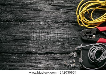Computer Network Laying Concept. Crimper Tool, Utp Cable, Net Switch And Connectors On Black Wooden 
