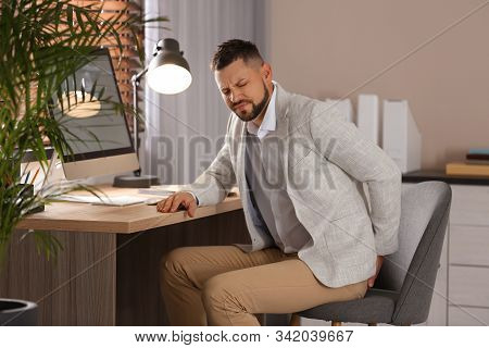 Man Suffering From Hemorrhoid At Workplace In Office