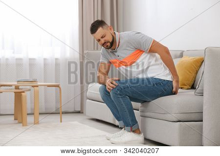 Man Suffering From Hemorrhoid On Sofa At Home