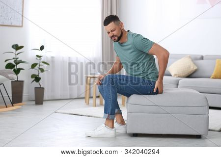 Man Suffering From Hemorrhoid In Living Room. Space For Text