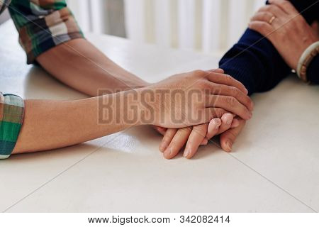 Close-up Image Of Young Man Holding Hand Of His Mother When Reassuring Her