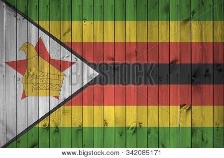 Zimbabwe Flag Depicted In Bright Paint Colors On Old Wooden Wall. Textured Banner On Rough Backgroun