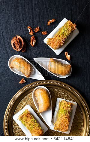Food Concept Oriental Arab Dessert Baklava Walnuts And Rolled Kanafeh On Black Slate Board With Copy