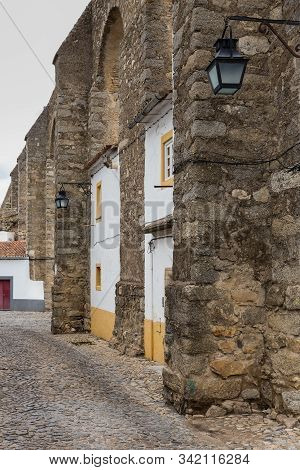 Agua De Prata. Houses Built Into The Arches Of The Evora Aqueduct. Portugal.