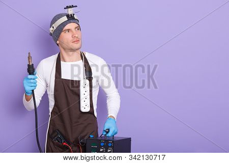 Technician Being Ready To Solder Something, Attractive Male Wears White Casual Shirt, Cap And Brown 