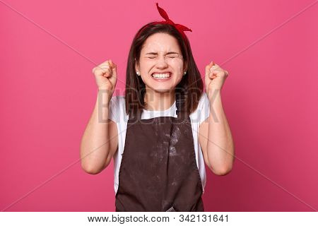 Housewife Female Wearing Brown Apron And White Casual T Shirt, Standing Isolated Over Rose Wall Back
