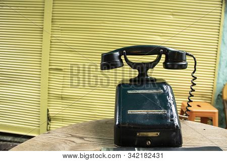 Old Black Telephone With Magneto On Desk. It Stands In The Middle Of The Street For Decorative Purpo
