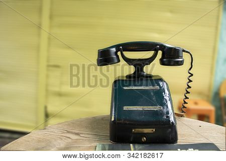 Old Black Telephone With Magneto On Desk. It Stands In The Middle Of The Street For Decorative Purpo