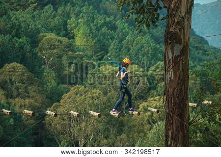 Canela, Brazil - July 21, 2019. Fully Equipped Girl Practicing Tree Climbing On Cloudy Day In A Fore