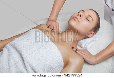 Masseur Makes A Relaxing Massage On The Face, Neck, Shoulders And Collarbones Of A Young Beautiful W