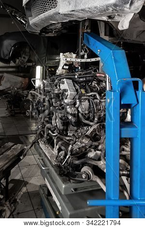 Used V8 Engine With Eight Cylinders Suspended Mounted On A Crane For Overhaul Repair And Installatio