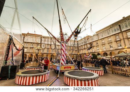 A Coruna, Spain. Dec 2012: Kids Enjoying And Bouncing A Slingshot Attraction In Plaza De Maria Pita 