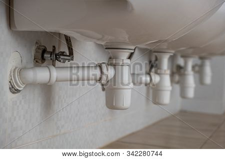 Close Up Of White Plastic Pipe Drain Under Washing Sink In Bathroom.