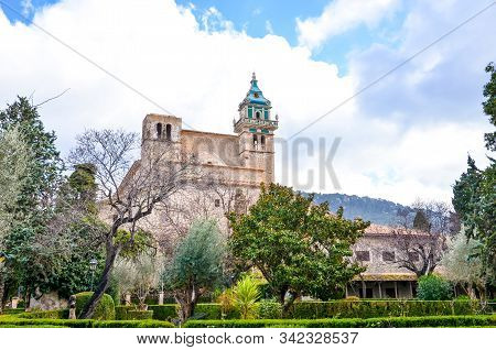 The Carthusian Monastery Of Valldemossa, In Valldemossa, Mallorca, Spain Surrounded By A Green Park 