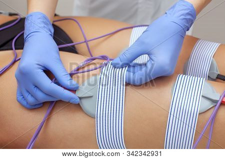 The Procedure Of Myostimulation On The Legs And Buttocks Of A Woman In A Beauty Salon. Overweight Tr