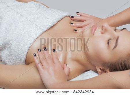 Masseur Makes A Relaxing Massage On The Face, Neck, Shoulders And Collarbones Of A Young Beautiful W
