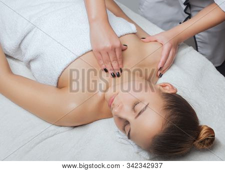 Masseur Makes A Relaxing Massage On The Face, Neck, Shoulders And Collarbones Of A Young Beautiful W