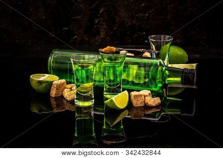 Absinthe Or Mint Liquor Shot. Absinthe In Glass With Lime Slices On Dark Background.