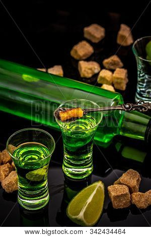 Absinthe Or Mint Liquor Shot. Absinthe In Glass With Lime Slices On Dark Background. Alcohol, Luxuri