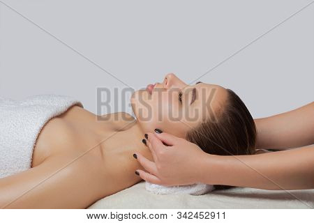 Masseur Makes A Relaxing Massage On The Ears, Face, Neck, Shoulders And Collarbones Of A Young Beaut