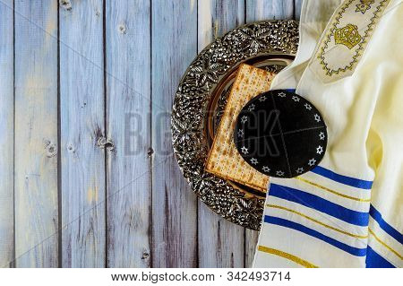 Matzoh Jewish Passover Bread In The Traditional Seder Plate With Kipah And Tallit Over Wooden Table