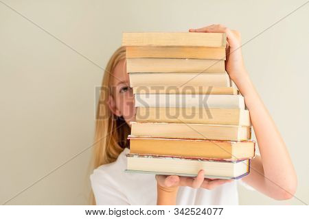 Teenage Girl Hiding Behind Big Pile Of Books She Wants To Read. Student Ready To Study Concept