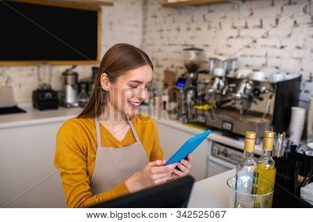 Smiling Cafe Employee Using The Tablet For Her Work
