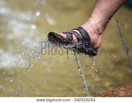 The Foot Of A Man In The Spray Of Water Of The Fountain In Summer.
