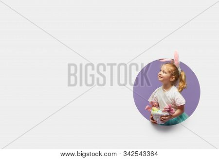 Easter Card. Cute Little Child Girl With Bunny Ears Holding Basket Of Easter Eggs. Child In A Round 
