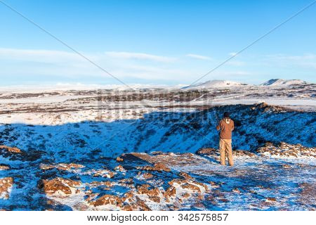 Amazing Winter Landscape Near Kerid Lake. The Guy Walks Near The Crater Of The Volcano Kerid In Wint