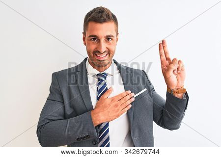 Young handsome business man wearing suit and tie over isolated background smiling swearing with hand on chest and fingers up, making a loyalty promise oath