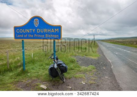 A Touring Bike Leaning Against A Sign Post On The Border Of County Durham, Northern England