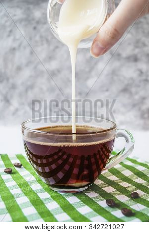 Transparent Cup Of Coffee With Pouring Condensed Milk