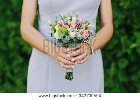The Bride Is Holding A Small Wedding Bouquet With Pink Roses, Eustoms And Greenery Close-up