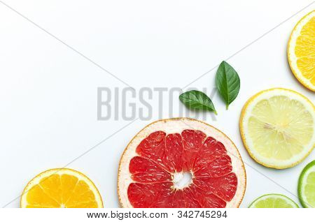 Flat Lay Composition With Slices Of Fresh Lemon Orange Grapefruit Lime Green Leaves On White Backgro