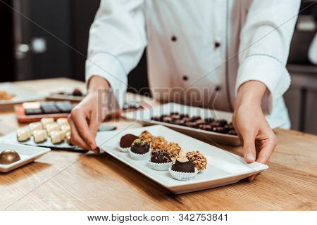 Cropped View Of Chocolatier Touching Plate With Sweet Fresh Chocolate Candies