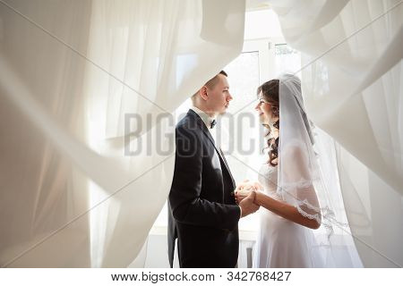 Beautiful Smiling Bride Wearing A Natural Flower Wreath And Standing In The Golden Summer Fields Wit