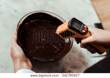 Cropped View Of Chocolatier Holding Cooking Thermometer Near Bowl With Dark Chocolate