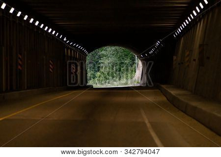 Curve Tunnel For Automobiles, Exit At Backgorund. Empty Engineering Construction With Rhythm Of Ligh